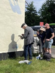 Ken White signing the mural - mahl stick at work