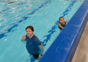 Holiday Club Half-Term Bookings Open - a Just For Fun Holiday Club leader supporting a child during one of the swimming sessions at the Dorcan venue. 