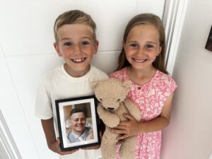 Little Hearts Big Kindness - Arthur and Elsie Morgan-Williams with photographs of their late father, Joe Morgan holding their baby sister Mabel’s teddy bear.  